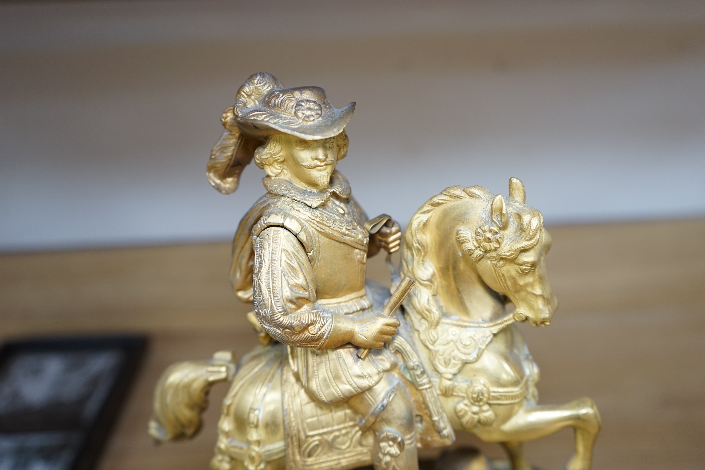 A late 19th century French ormolu mantel clock surmounted with a cavalier on horseback, key and pendulum, 38cm. Condition - fair to good